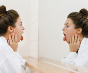 woman looking at her tongue in the mirror